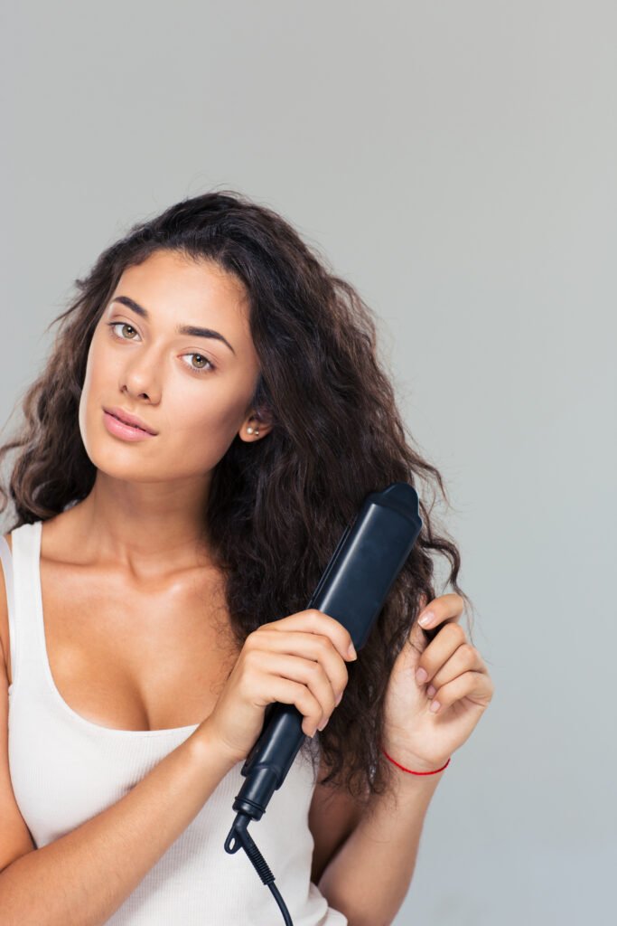 Woman doing hairstyle with hair straightener